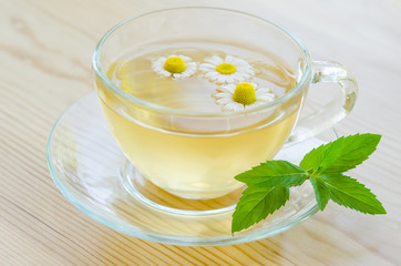 Obraz na płótnie Canvas Cup of medicinal chamomile tea on the wooden table