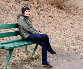 Fototapeta premium Young beautiful woman sitting on bench in park.