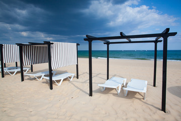 Different parasols and sun loungers on the empty beach on Tavira
