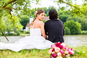 Bridal pair with bouquet on meadow at river