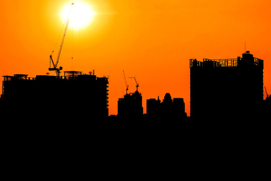 Construction crane and skyscraper at sunset