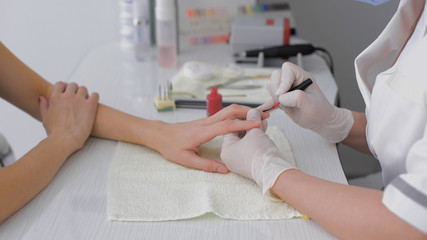 Close-up of beautician applying red varnish