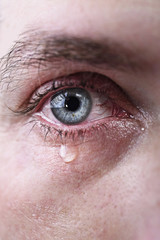 close up of blue eye of man crying in tears sad and full of pain in depression