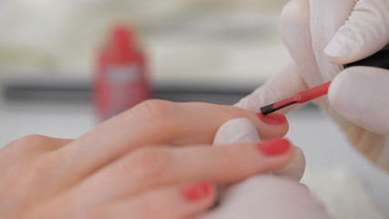 Close-up of beautician applying red varnish