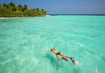 Woman snorkeling in clear tropical waters in front of exotic isl