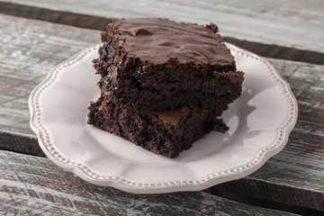 Decadent dark chocolate chip brownie on an antique plate on an old weathered barn wood table