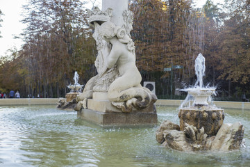 Fototapeta na wymiar stone fountain with bronze figures in the Jardin del Retiro in M