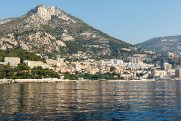 Fototapeta premium Color DSLR stock image of luxury apartment buildings and condominiums on the rocky, mountainous Mediterranean coast of the French Riviera. Horizontal with copy space for text 
