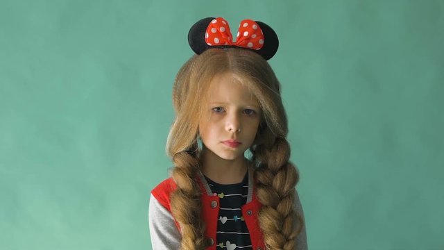 Little girl with braids and a bow in her hair. Posing in the studio 