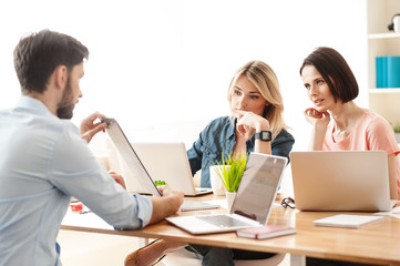 Cheerful three workers are discussing new project