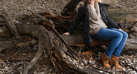 Mujer feliz sentada en tronco.