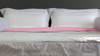 Fototapeta na wymiar Close up white and pink bedding sheets and pillow on black wooden.