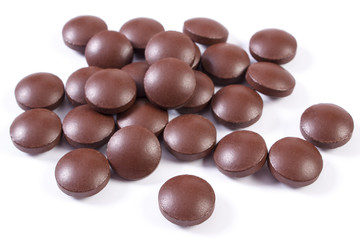 Brown medical tablets and capsules on white background, health care concept