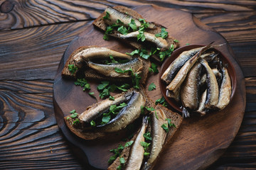 Smoked sprats with chopped parsley and brown bread, close-up