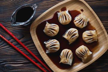 Above view of dim-sums with soy sauce served in a bamboo tray