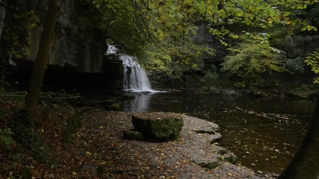Picturesque waterfall in the forest with autumn leaves.