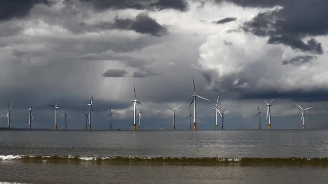 Row of wind turbines in the sea. Panning right.