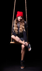 Portrait of beautiful model in red hat and jacket posing on rope