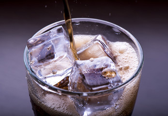 Pooring soft drink in a glass with ice