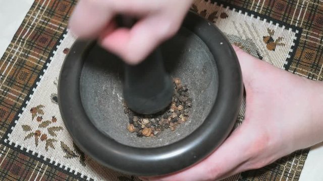 Black pepper is grinded in a stone mortar