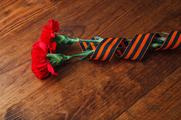 two red flower and St. George's ribbon on wooden background