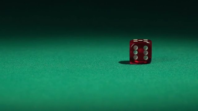 Closeup view of red casino dice rolling on green surface in slow-motion
