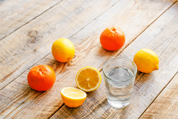 composition of lemons, oranges and glass with water  wooden table
