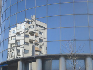 Block of apartments reflected on glass wall of administrative building