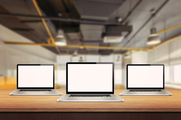Three laptop devices on table in office interior. Isolated white screen for mockup presentation