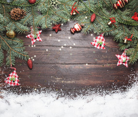 Christmas or New Year decoration background: fur-tree branches, colorful glass balls and glittering stars on wooden background, top view, copy space.