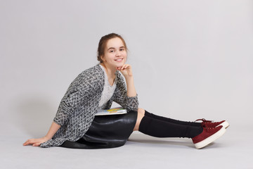 Girl teenager with book sitting on the floor and smiling.
