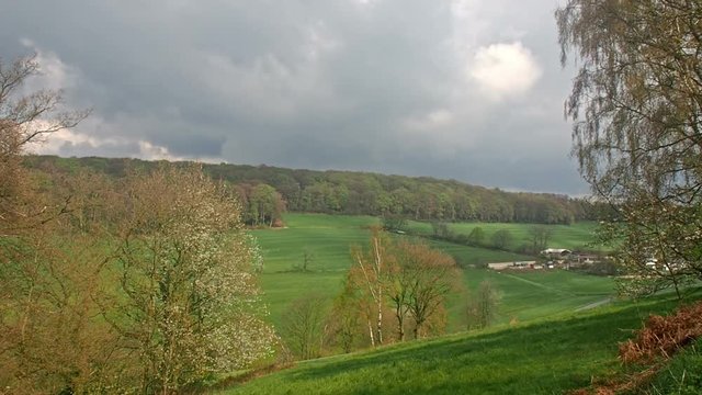 Clouds over a valley and a farm.
A forest on the hill and fields in the valley in the German town Velbert.
