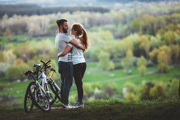 Beautiful young loving couple hugging at sunset, there are two bikes. The concept of happiness, peace and love