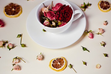 dried flowers dried roses and round slices of lemon laid on a white background and the white Cup