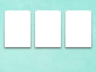 Close-up of three nailed blank frames on aqua plastered concrete wall background