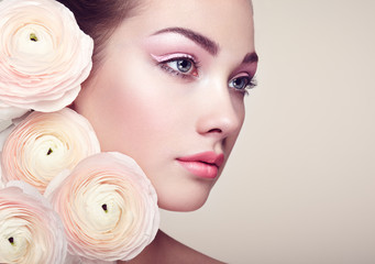Naklejka premium Portrait of beautiful young woman with flowers. Brunette woman with luxury makeup. Perfect skin. Eyelashes. Cosmetic eyeshadow