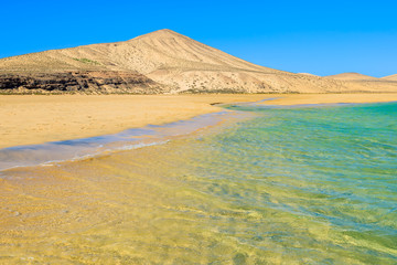 Fototapeta na wymiar Beautiful Sotavento beach on southern coast of Fuerteventura and sand dunes in the background, Canary Islands, Spain