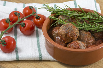 Tasty croquettes with rosemary and cherry on kitchen towel in clay bowl