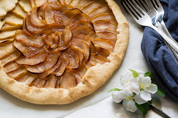 Open pie or galette with apples decorated apple blossom on grey metalic desk