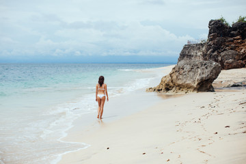 Beautiful girl in swimsuit walking along the beach.back view