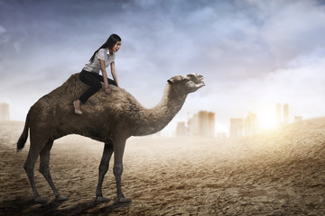 Image of asian business woman riding camel