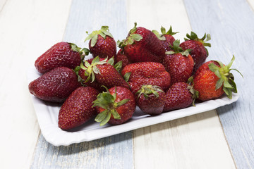 Fresh strawberry on a plate on a blue gray background