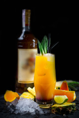 Beautiful and original cold cocktail with slices of fresh orange and lime, whiskey and ice cubes