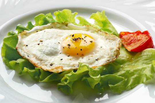 Fried egg with tomato on green salad leaf
