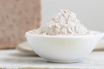 Bowl with flour on a wooden table and some bread. Empty copy space for editor's text.