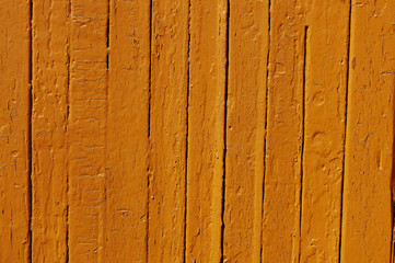 Fototapeta na wymiar Orange flaky paint on a wooden fence.