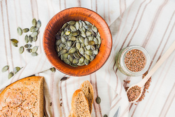 raw pumpkin seeds in a clay plate, linen napkin, healthy snack