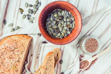 raw pumpkin seeds in a clay plate, linen napkin, healthy snack