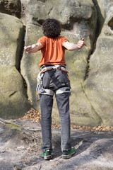 Young man climbs on a cliff with a rope.
