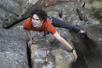 Young male climber hanging by a cliff.